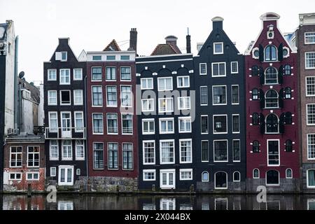 L'iconica fila di case sui canali di Amsterdam, con le loro distintive facciate a timpano e il riflesso nelle acque calme, che incarna l'architettura urbana olandese. Foto Stock