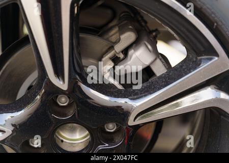 Una vista dettagliata di una ruota di un'auto che mostra una pastiglia dei freni nelle immediate vicinanze, evidenziando i componenti meccanici dell'impianto frenante. Foto Stock