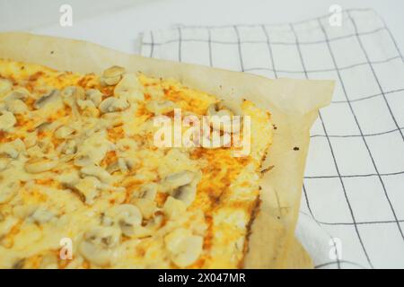 Una vista dettagliata di una pizza appena sfornata condita con funghi a fette, con crosta dorata e condimenti salati. Foto Stock