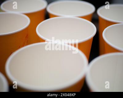 I bicchieri di carta arancioni vuoti sono in fila. Prepararsi per una festa. Prodotto ecologico. Niente plastica. Primo piano. Foto Stock