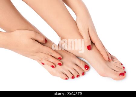 Donna che mostra eleganti unghie del piede dopo la procedura di pedicure e mani curate con smalto rosso isolato su bianco, primo piano Foto Stock