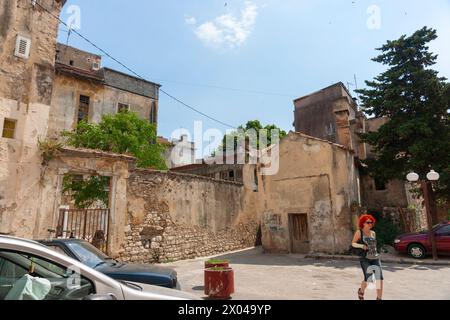 Zara Croazia - maggio 26 2011; donna con i capelli rossi cammina dall'altra parte della strada circondata da vecchi edifici. Foto Stock