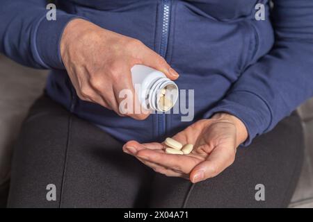 Le mani di una donna anziana versano pillole dalla bottiglia alla plam. Primo piano. Foto Stock