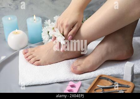 Donna con unghie dei piedi pulite dopo la procedura di pedicure su tessuto grigio setoso, primo piano Foto Stock