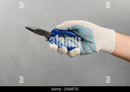 Uomo con pinze a becchi tondi su sfondo grigio, primo piano Foto Stock