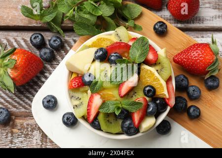 Gustosa Macedonia di frutta nel recipiente e ingredienti su un tavolo di legno, in piano Foto Stock