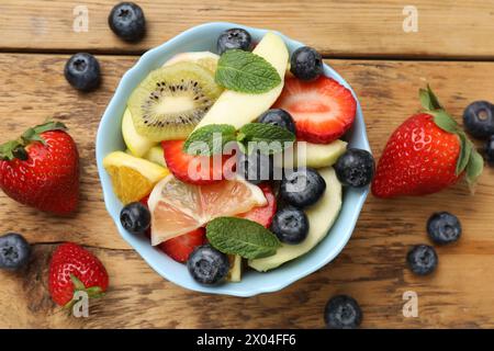 Gustosa Macedonia di frutta nel recipiente e ingredienti su un tavolo di legno, in piano Foto Stock