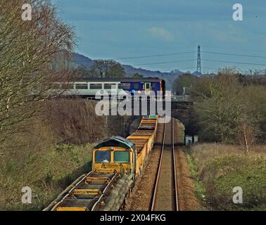 Il servizio ferroviario Northern del 14,10 da Preston a Ormskirk attraversa una lunga linea di treni ingegneristici al Burscough Bridge martedì 19.3,2024. Foto Stock