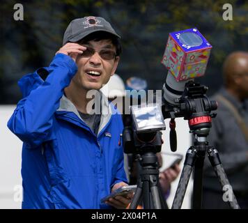 Washington, Stati Uniti d'America. 8 aprile 2024. Washington, Stati Uniti d'America. 8 aprile 2024. Un uomo copre le sue telecamere con filtri protettivi mentre scatta una foto dell'eclissi solare durante una festa di osservazione al National Mall, l'8 aprile 2024, a Washington, DC Un'eclissi solare totale ha attraversato una stretta porzione del continente nordamericano dal Messico alla costa atlantica di Terranova, in Canada. Crediti: Bill Ingalls/NASA/Alamy Live News Foto Stock