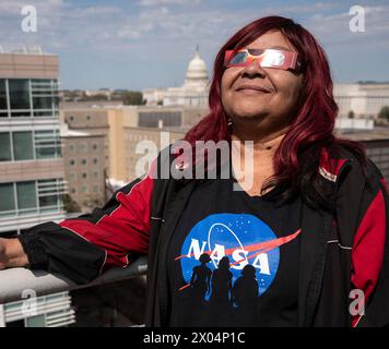 Washington, Stati Uniti d'America. 8 aprile 2024. Washington, Stati Uniti d'America. 8 aprile 2024. Gli spettatori che indossano occhiali protettivi guardano in alto mentre la luna copre la parte anteriore del Sole durante la festa di osservazione di un'eclissi solare presso il quartier generale della NASA, l'8 aprile 2024, a Washington, DC Un'eclissi solare totale ha attraversato una stretta porzione del continente nordamericano dal Messico alla costa atlantica di Terranova, in Canada. Crediti: Connie Moore/NASA/Alamy Live News Foto Stock