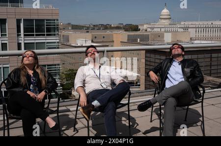 Washington, Stati Uniti d'America. 8 aprile 2024. Washington, Stati Uniti d'America. 8 aprile 2024. Gli spettatori che indossano occhiali protettivi guardano in alto mentre la luna copre la parte anteriore del Sole durante la festa di osservazione di un'eclissi solare presso il quartier generale della NASA, l'8 aprile 2024, a Washington, DC Un'eclissi solare totale ha attraversato una stretta porzione del continente nordamericano dal Messico alla costa atlantica di Terranova, in Canada. Crediti: Connie Moore/NASA/Alamy Live News Foto Stock