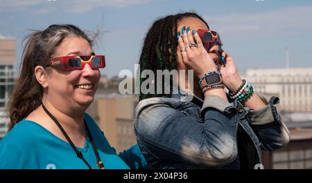 Washington, Stati Uniti d'America. 8 aprile 2024. Washington, Stati Uniti d'America. 8 aprile 2024. Gli spettatori che indossano occhiali protettivi guardano in alto mentre la luna copre la parte anteriore del Sole durante la festa di osservazione di un'eclissi solare presso il quartier generale della NASA, l'8 aprile 2024, a Washington, DC Un'eclissi solare totale ha attraversato una stretta porzione del continente nordamericano dal Messico alla costa atlantica di Terranova, in Canada. Crediti: Connie Moore/NASA/Alamy Live News Foto Stock