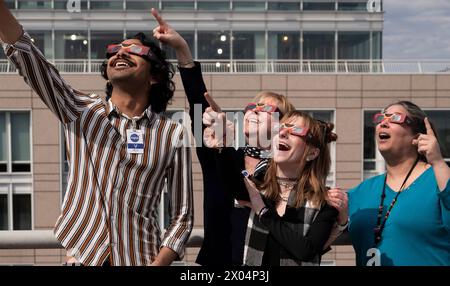 Washington, Stati Uniti d'America. 8 aprile 2024. Washington, Stati Uniti d'America. 8 aprile 2024. Gli spettatori che indossano occhiali protettivi guardano in alto mentre la luna copre la parte anteriore del Sole durante la festa di osservazione di un'eclissi solare presso il quartier generale della NASA, l'8 aprile 2024, a Washington, DC Un'eclissi solare totale ha attraversato una stretta porzione del continente nordamericano dal Messico alla costa atlantica di Terranova, in Canada. Crediti: Connie Moore/NASA/Alamy Live News Foto Stock