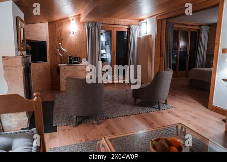 Accogliente soggiorno interno in legno con poltrone, tavolino da caffè in vetro e sculture di cervi. Foto Stock