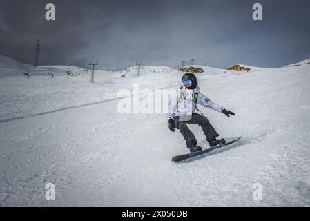 Snowboarder in azione su piste innevate in condizioni meteorologiche avverse presso una stazione sciistica sviluppata. Foto Stock