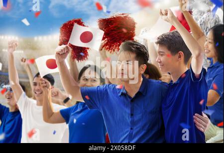 Tifoso di calcio giapponese nello stadio. Tifosi giapponesi sul campo da calcio che guardano le partite di squadra. Gruppo di tifosi con bandiera e maglia nazionale Foto Stock