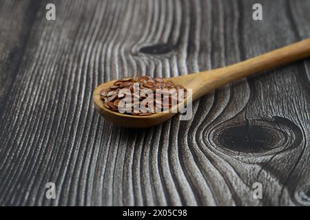 Semi di lino. Polvere di semi di lino in un cucchiaio di legno. In piedi su uno sfondo di legno. Foto Stock