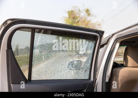 Vetro del finestrino laterale dell'auto incrinato su strada. Finestrino dell'auto danneggiato. Richieste di indennizzo per incidenti stradali tramite app assicurative. Foto Stock