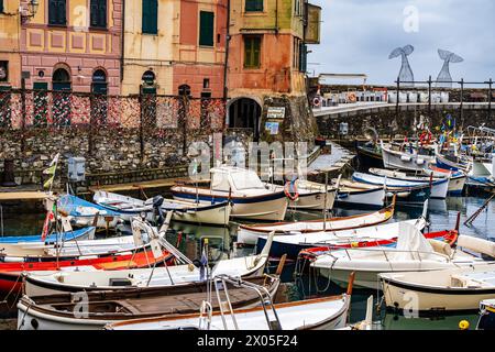 Barche da pesca nel porto di Camogli in Italia che si riflettono sull'acqua con i colorati e antichi appartamenti in primo piano. Foto Stock