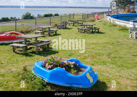 Pedalò riadattato trasformato in piantatrice con fiori colorati sull'erba accanto alla piscina per barche Royal Esplanade, Ramsgate, che si affaccia sul mare. Foto Stock