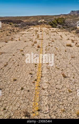 Sezione abbandonata dell'autostrada US-180, US-62 con overgrowth, Guadalupe Mountains in lontananza, Texas, USA Foto Stock