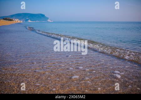 Bel mare calmo in una giornata di sole. Primo piano dello shot di surf Sea light. Una piccola onda e una schiuma marina brillano al sole. Foto Stock