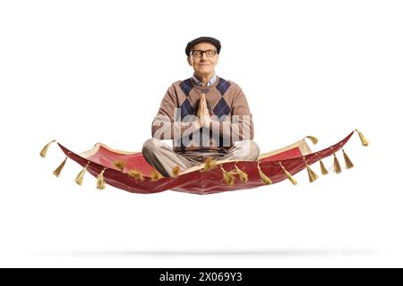 Uomo anziano seduto su un tappeto magico e che pratica una posa yoga isolata su sfondo bianco Foto Stock