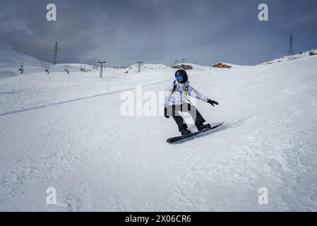 Snowboarder in azione su piste innevate in condizioni meteorologiche avverse presso una stazione sciistica sviluppata. Foto Stock