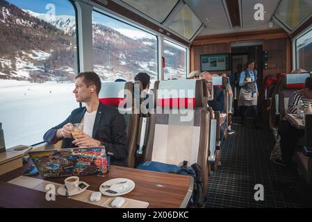 Treno alpino interno con un giovane che guarda fuori dalla finestra sul Glacier Express, Svizzera. Foto Stock