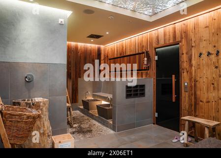 Moderno bagno in legno e piastrelle con lucernario, panca e pantofole in un ambiente tranquillo Foto Stock