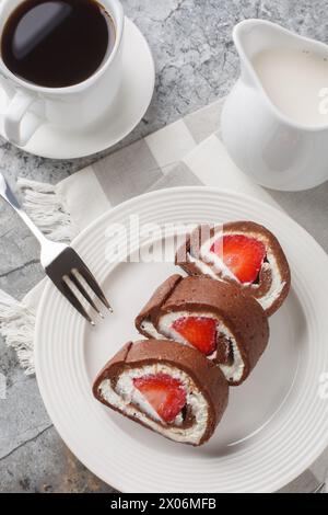 Dolce torta al cioccolato ripiena di fragole e formaggio spalmabile servito con caffè da vicino sul tavolo. Vista dall'alto verticale Foto Stock