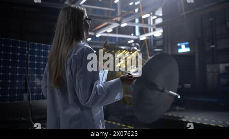 Ingegnere industriale femminile che lavora alla costruzione di satelliti artificiali. Agenzia aerospaziale: Scienziato che utilizza il computer per sviluppare veicoli spaziali per l'esplorazione spaziale e la comunicazione dei dati. Foto Stock