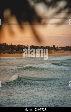 Sydney Sunset Serenity: Montagne maestose, onde oceaniche, sabbie arancioni e alberi verdeggianti nella Glow of Dusk Foto Stock