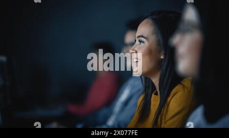 Gruppo multietnico di studenti di sesso femminile e maschile seduti nella sala del college, che collaborano a progetti scolastici su un computer. Giovani studiosi studiano, parlano, applicano competenze accademiche e conoscenze in classe. Foto Stock