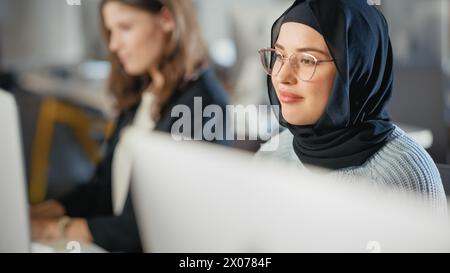 Bellissimo Ritratto di una studentessa musulmana a Hijab, che studia all'università. Lavora su computer desktop all'università. Applicare le proprie conoscenze per acquisire competenze accademiche in classe. Foto Stock
