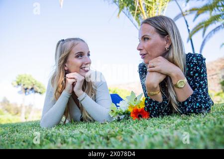 Madre e figlia stanno facendo una conversazione mentre si stendono sull'erba. Foto Stock