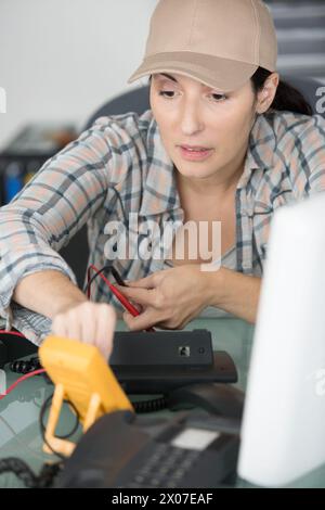 donna che controlla la tensione di un dispositivo elettronico Foto Stock