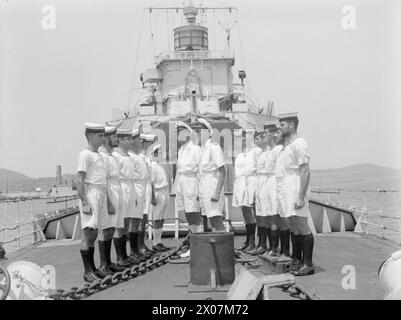 LA TRIPLICE CELEBRAZIONE DELLA HMS WOLVERINE. MARZO 1944, FREETOWN. LA HMS WOLVERINE, UNA DESTROYER DI 25 ANNI, HA RECENTEMENTE CELEBRATO TRE "COMPLEANNI" SPECIALI. HA PERCORSO 200.000 MIGLIA DALL'INIZIO DELLA GUERRA, HA COMPLETATO UN ANNO DI SERVIZIO NELLA STAZIONE DELL'AFRICA OCCIDENTALE E HA APPENA PORTATO IL SUO 100° CONVOGLIO IN SICUREZZA A HARBOR. - Ispezione prima delle divisioni domenicali, classificazione della HMS WOLVERINE da parte del primo tenente e ufficiale di divisione Foto Stock