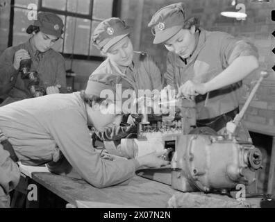 Le donne del servizio territoriale ausiliario ispezionano un motore in un'officina di trasporto di motori come parte della formazione a Camberley, Surrey, 1941. Foto Stock