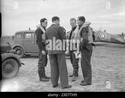 LA BATTAGLIA DELLA GRAN BRETAGNA 1940 - i piloti del No. 19 Squadron riferiscono all'ufficiale dell'intelligence (di nuovo alla telecamera) a Fowlmere, settembre 1940. I piloti sono (da sinistra a destra): Il capo squadrone Brian 'Sandy' Lane (CO), il tenente di volo Walter 'Farmer' Lawson e il sergente David Lloyd Royal Air Force, 19 Squadron Foto Stock