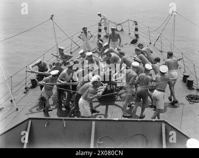 LA TRIPLICE CELEBRAZIONE DELLA HMS WOLVERINE. MARZO 1944, FREETOWN. LA HMS WOLVERINE, UNA DESTROYER DI 25 ANNI, HA RECENTEMENTE CELEBRATO TRE "COMPLEANNI" SPECIALI. HA PERCORSO 200.000 MIGLIA DALL'INIZIO DELLA GUERRA, HA COMPLETATO UN ANNO DI SERVIZIO NELLA STAZIONE DELL'AFRICA OCCIDENTALE E HA APPENA PORTATO IL SUO 100° CONVOGLIO IN SICUREZZA A HARBOR. - Per la melodia della canzone picchiaduro suonata su un gramafone portatile, gli uomini del WOLVERINE, il capstan foriero, troppo bravo nell'ancora Foto Stock