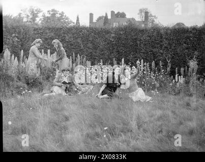Nel 1944, le lavoratrici di guerra si rilassano sull'erba e leggono o ispezionano i lupini nel giardino di una casa di riposo a Walton-on-the-Hill, Surrey, Inghilterra. Foto Stock