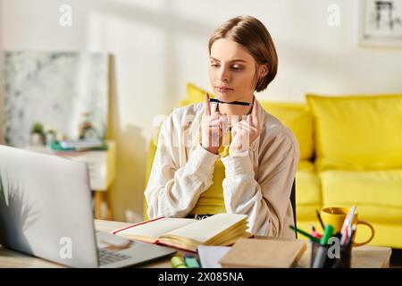 Una ragazza adolescente seduta con attenzione davanti al suo portatile, coinvolta nell'e-learning e nello studio da casa. Foto Stock