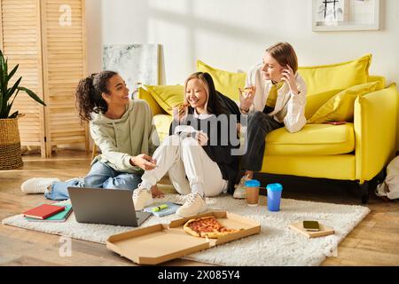 Un gruppo di diverse ragazze adolescenti che chiacchierano e ridevano sedute sul pavimento accanto a un vibrante divano giallo in un ambiente accogliente. Foto Stock