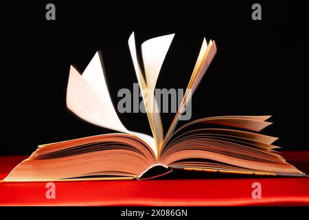 Le pagine di un libro spesso vengono attivate su uno sfondo rosso e nero. Foto Stock