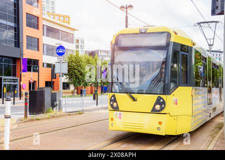 Tram giallo in movimento lungo una strada in un quartiere periferico Foto Stock