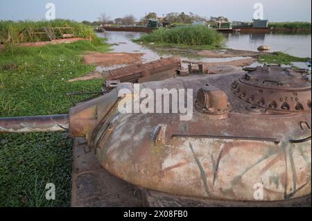 SUDAN DEL SUD, Stato dell'alto Nilo, città Renk, fiume Nilo bianco, relitto abbandonato del carro armato da battaglia sovietico T-54 dell'SPLA Sudan Peoples Liberation Army dalla seconda guerra civile sudanese con il Sudan del Nord SAF Sudan Armed Forces, dietro la chiatta fluviale per il trasporto di merci e passeggeri a Malakal Foto Stock