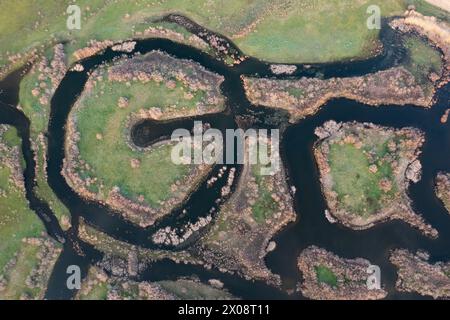 Lo scatto aereo cattura gli intricati meandri e la lussureggiante vegetazione del fiume Ciguera, circondato dal paesaggio pastorale di Ciudad Real, Spagna. Foto Stock