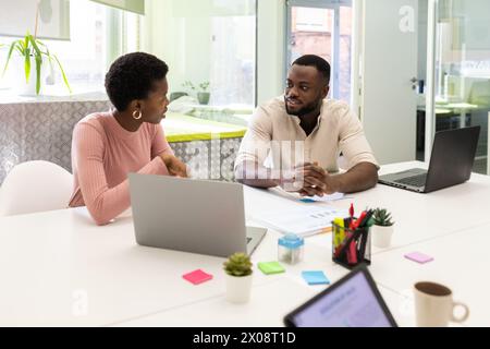 Due professionisti afroamericani si sono impegnati in una conversazione in un ufficio moderno. Foto Stock
