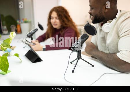 Il podcast multietnico ospita registrazioni in studio, con donna asiatica e uomo afroamericano. Foto Stock